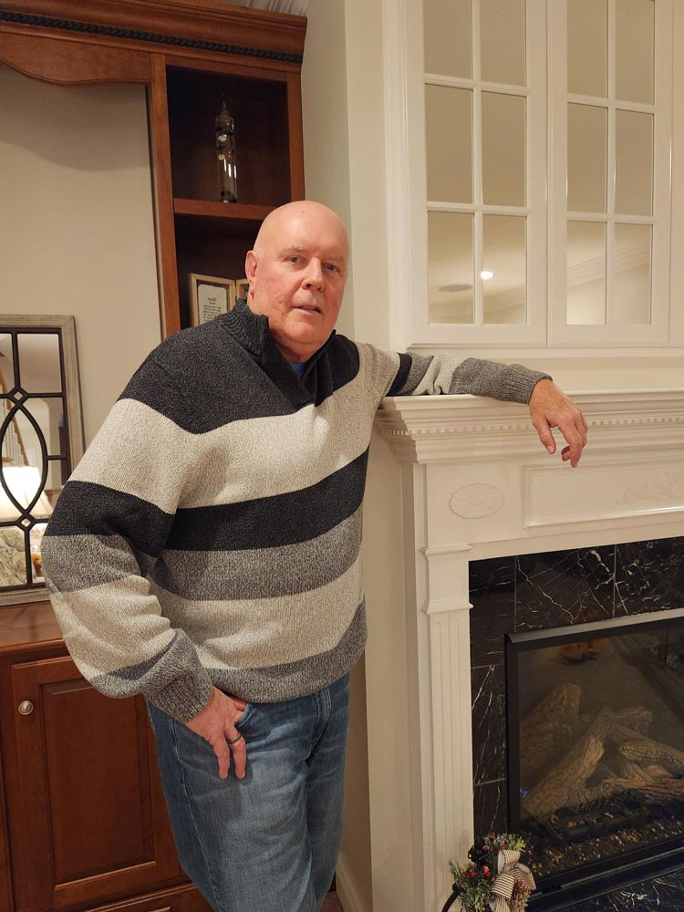 Portrait photo of Mark leaning against a fireplace mantel